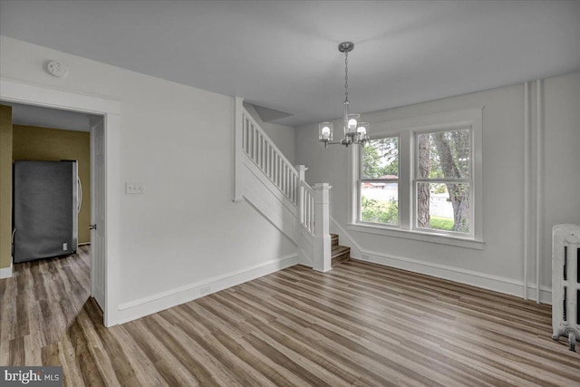 937 Fern Ave, Reading, PA 19607 - unfurnished living room with wood finished floors, stairway, baseboards, a chandelier, and radiator