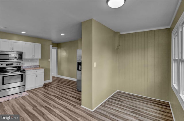937 Fern Ave, Reading, PA 19607 - kitchen with appliances with stainless steel finishes, baseboards, light wood-style flooring, white cabinetry, and backsplash