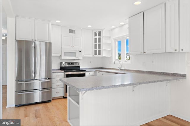 1131 Long Beach Blvd, Long Beach Township, NJ 08008 - kitchen with appliances with stainless steel finishes, open shelves, a peninsula, light wood finished floors, and white cabinetry