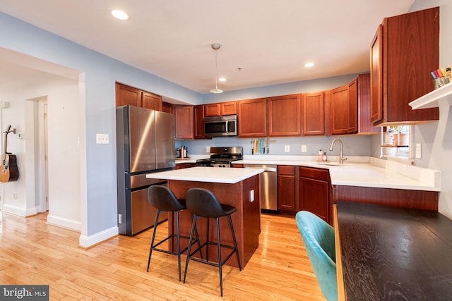 3111 Tilden Dr, Baltimore, MD 21211 - kitchen with appliances with stainless steel finishes, a sink, a breakfast bar, baseboards, and light wood finished floors