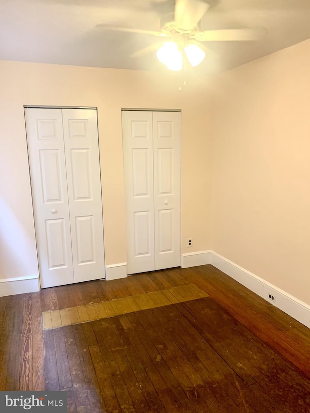 42 E 5th St, New Castle, DE 19720 - unfurnished bedroom with multiple closets, dark wood finished floors, and a ceiling fan