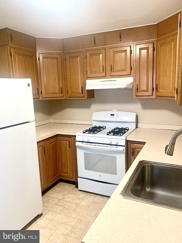 42 E 5th St, New Castle, DE 19720 - kitchen with white appliances, under cabinet range hood, light countertops, and brown cabinetry