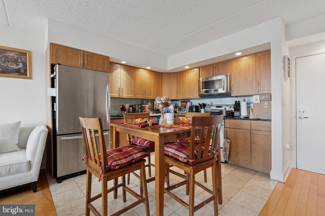 200 Lombard St Unit 728, Philadelphia, PA 19147 - kitchen featuring stainless steel appliances, backsplash, dark countertops, a textured ceiling, and brown cabinets