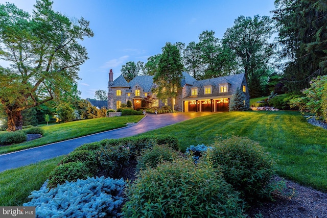 1412 Mount Pleasant Rd, Villanova, PA 19085 - view of front of home with a front yard, stone siding, an attached garage, a chimney, and driveway