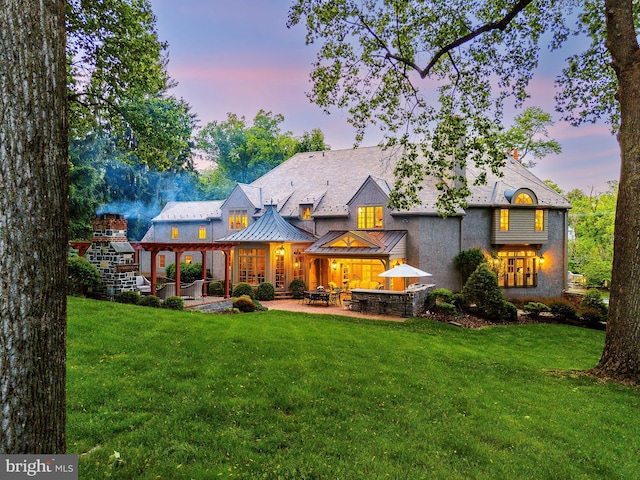 1412 Mount Pleasant Rd, Villanova, PA 19085 - back of property at dusk featuring a standing seam roof, a patio, a yard, and stucco siding