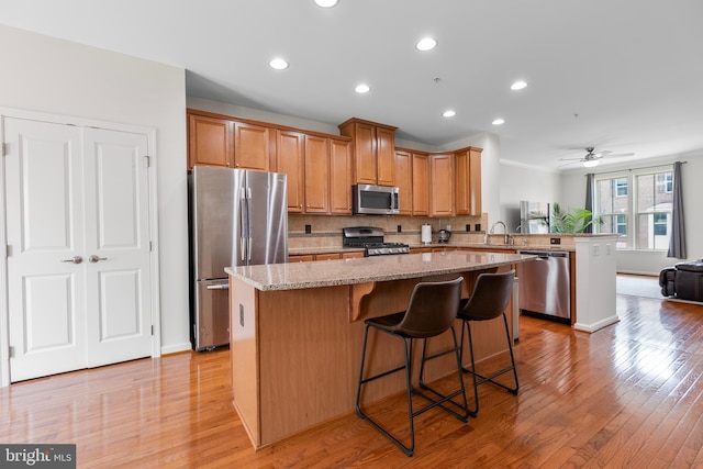 9161 Landon House Ln, Frederick, MD 21704 - kitchen with appliances with stainless steel finishes, a peninsula, a center island, open floor plan, and light wood-style flooring