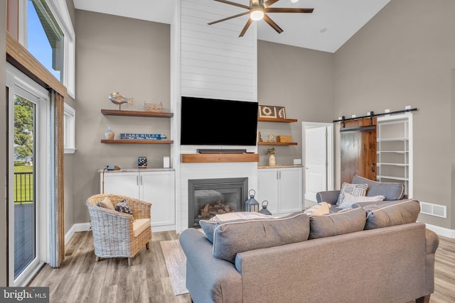 61 Bragg Dr, East Berlin, PA 17316 - living area with high vaulted ceiling, a ceiling fan, light wood-style floors, a large fireplace, and a barn door