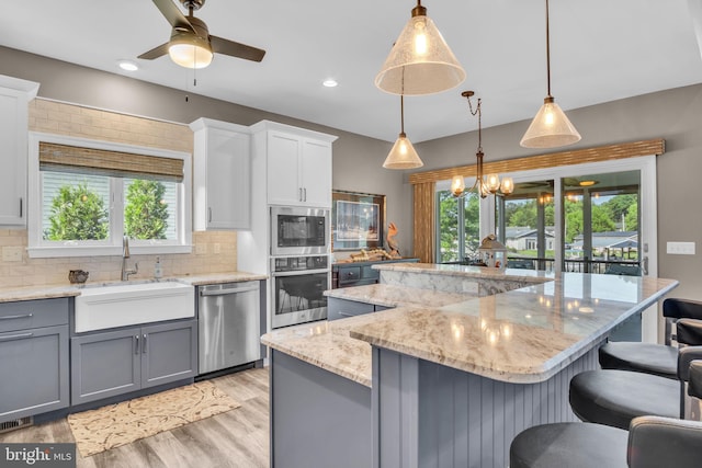 61 Bragg Dr, East Berlin, PA 17316 - kitchen with stainless steel appliances, gray cabinetry, decorative backsplash, a kitchen bar, and a ceiling fan