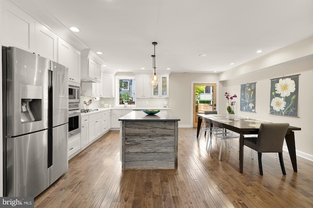 1217 Carrollsburg Pl SW, Washington, DC 20024 - kitchen featuring stainless steel appliances, white cabinetry, a kitchen island, decorative backsplash, and plenty of natural light
