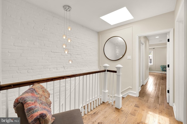 1217 Carrollsburg Pl SW, Washington, DC 20024 - hall featuring a skylight, brick wall, light wood-style flooring, an upstairs landing, and baseboards