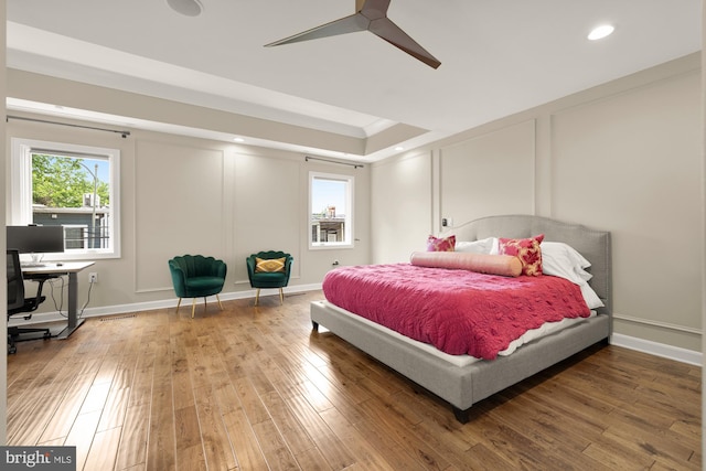 1217 Carrollsburg Pl SW, Washington, DC 20024 - bedroom with wood finished floors, recessed lighting, a decorative wall, a tray ceiling, and a ceiling fan