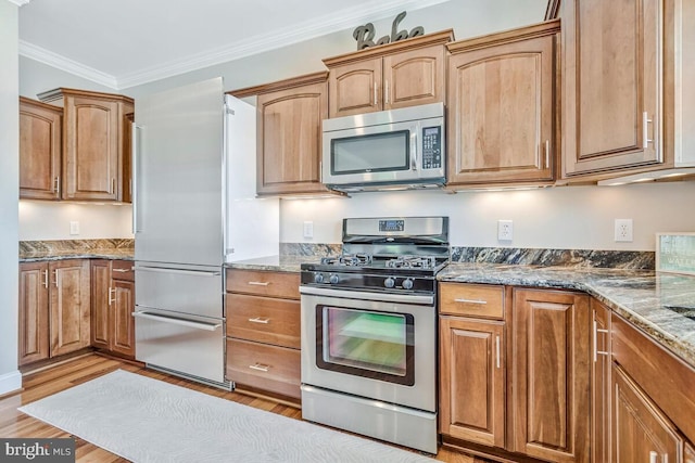 3300 Shore Dr, Annapolis, MD 21403 - kitchen with appliances with stainless steel finishes, dark stone countertops, light wood-style flooring, crown molding, and brown cabinetry