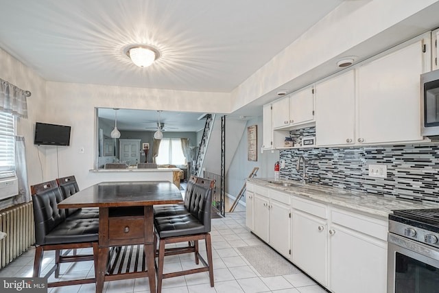 3725 King Ave, Pennsauken, NJ 08110 - kitchen featuring light tile patterned flooring, decorative backsplash, ceiling fan, white cabinetry, and appliances with stainless steel finishes