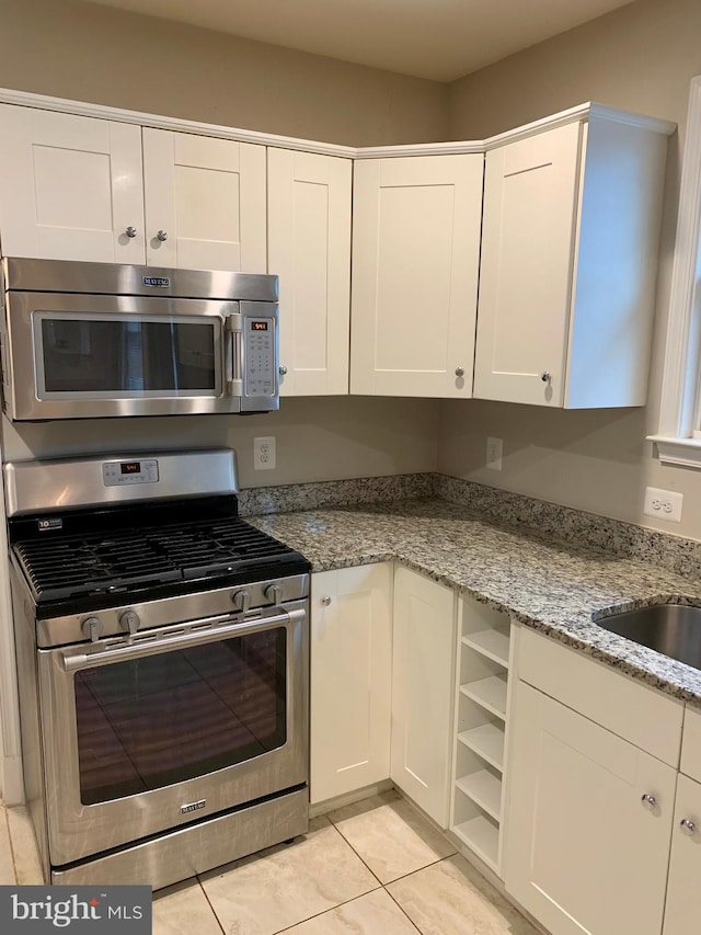 3528 14th St N, Arlington, VA 22201 - kitchen featuring stainless steel appliances, white cabinetry, light stone countertops, and light tile patterned flooring