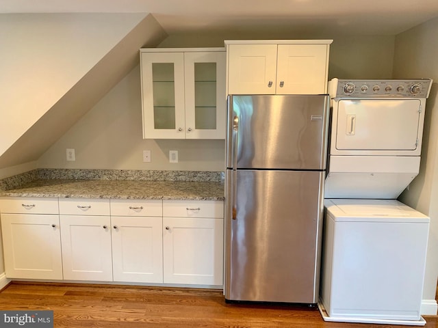 3528 14th St N, Arlington, VA 22201 - kitchen with freestanding refrigerator, stacked washer and clothes dryer, wood finished floors, white cabinetry, and glass insert cabinets
