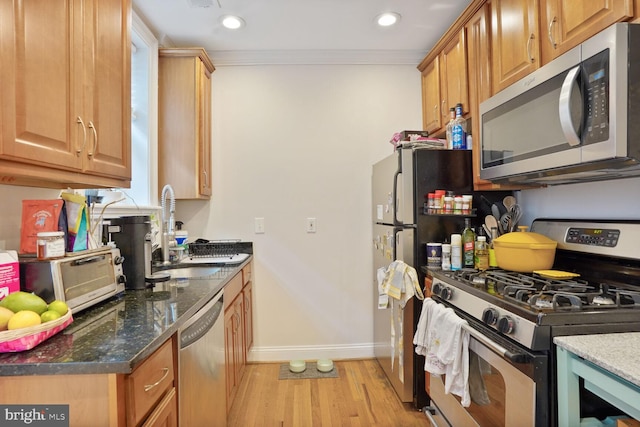 1443 Oak St NW Unit 102, Washington, DC 20010 - kitchen with appliances with stainless steel finishes, a sink, light wood-style flooring, baseboards, and dark stone counters