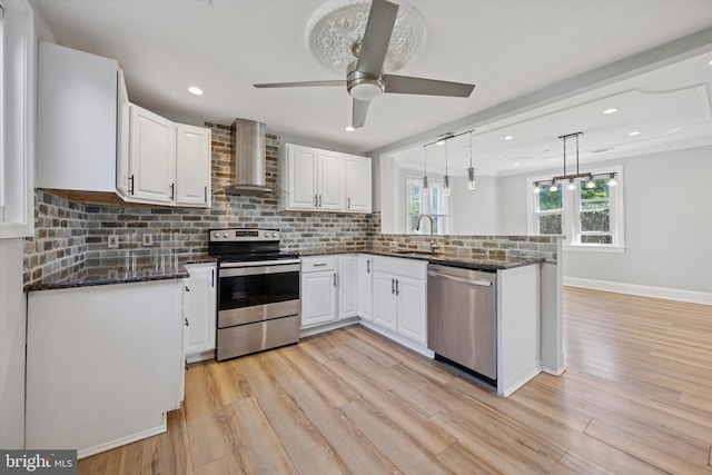 722 Mason Ave, Drexel Hill, PA 19026 - kitchen featuring stainless steel appliances, wall chimney range hood, a sink, a peninsula, and white cabinetry