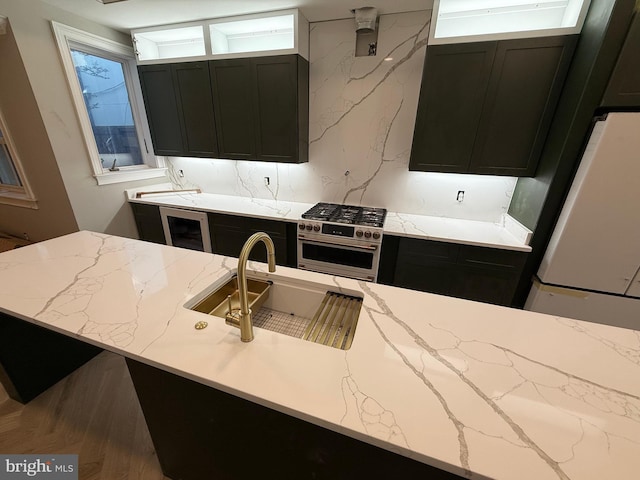 422 11th St SE, Washington, DC 20003 - kitchen featuring dark cabinets, high end stainless steel range oven, a sink, light stone countertops, and freestanding refrigerator