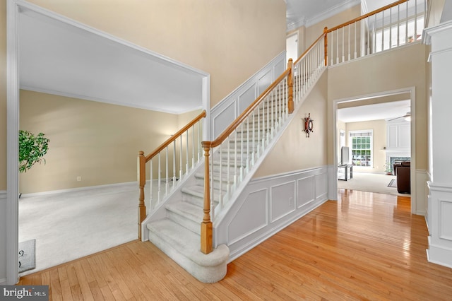 859 Empress Rd, West Chester, PA 19382 - stairway with hardwood / wood-style floors, a fireplace, crown molding, a wainscoted wall, and a decorative wall