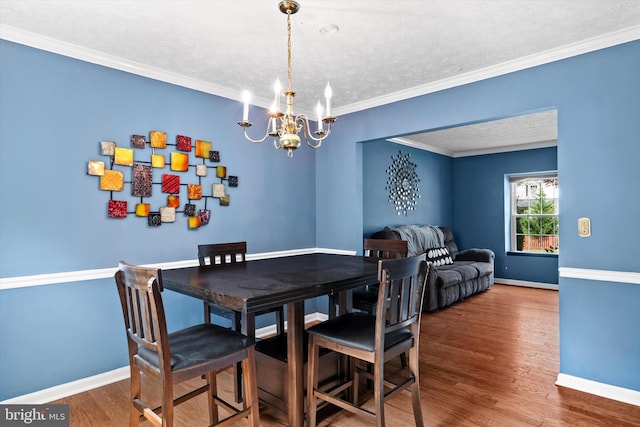 10462 Brackets Ford Cir, Manassas, VA 20110 - dining space with a chandelier, baseboards, wood finished floors, ornamental molding, and a textured ceiling