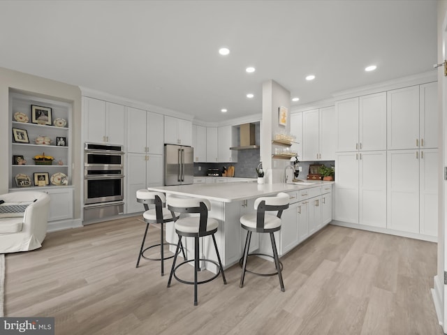 8101 Connecticut Ave Unit S 608, Chevy Chase, MD 20815 - kitchen featuring appliances with stainless steel finishes, wall chimney range hood, a peninsula, light countertops, and white cabinets