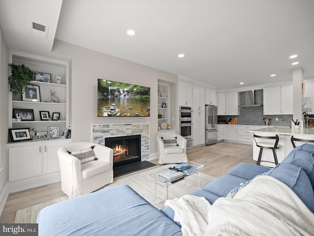 8101 Connecticut Ave Unit S 608, Chevy Chase, MD 20815 - living area featuring light wood finished floors, a tiled fireplace, built in shelves, and recessed lighting