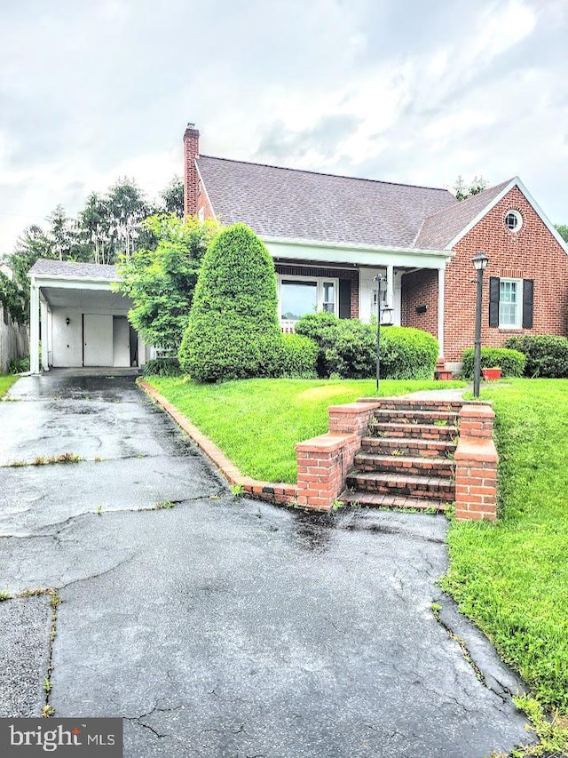 612 S Thomas St, Bedford, PA 15522 - view of front of house featuring a front lawn, a chimney, asphalt driveway, brick siding, and an attached carport