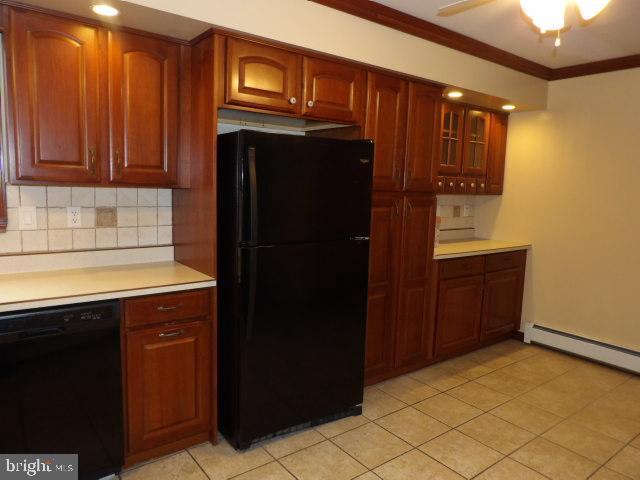 612 S Thomas St, Bedford, PA 15522 - kitchen featuring black appliances, tasteful backsplash, light countertops, light tile patterned floors, and glass insert cabinets