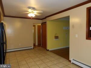 612 S Thomas St, Bedford, PA 15522 - spare room featuring baseboard heating, ceiling fan, ornamental molding, a baseboard heating unit, and light tile patterned floors