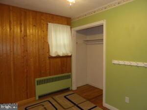 612 S Thomas St, Bedford, PA 15522 - unfurnished bedroom with radiator and wood walls