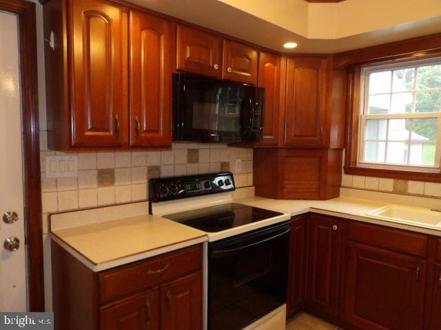 612 S Thomas St, Bedford, PA 15522 - kitchen featuring black microwave, range with electric cooktop, backsplash, and light countertops