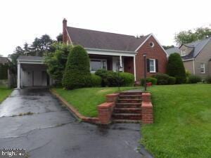 612 S Thomas St, Bedford, PA 15522 - view of front of house featuring asphalt driveway, a front lawn, a chimney, and an attached carport