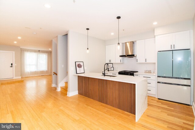 618 N American St, Philadelphia, PA 19123 - kitchen with freestanding refrigerator, wall chimney exhaust hood, a sink, white cabinetry, and light wood-style flooring
