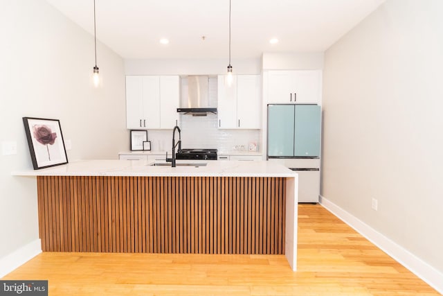 618 N American St, Philadelphia, PA 19123 - kitchen with freestanding refrigerator, wall chimney range hood, a sink, white cabinets, and decorative light fixtures