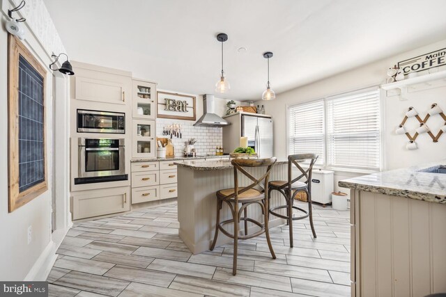389 Cypress St, Millington, MD 21651 - kitchen with stainless steel appliances, wall chimney range hood, tasteful backsplash, hanging light fixtures, and a kitchen bar