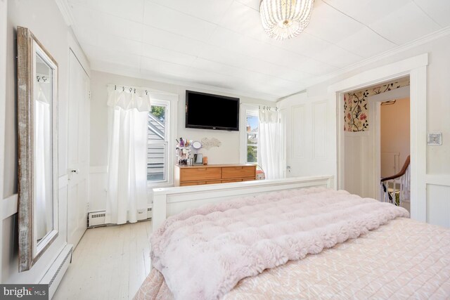389 Cypress St, Millington, MD 21651 - bedroom with multiple windows, crown molding, light wood-type flooring, a wainscoted wall, and a baseboard radiator