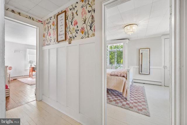 389 Cypress St, Millington, MD 21651 - hall featuring a wainscoted wall, a baseboard heating unit, wood finished floors, a decorative wall, and a chandelier