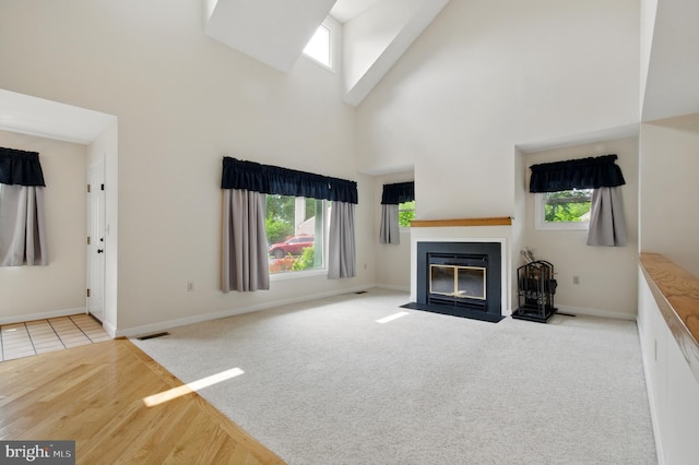 5762 Lichenbark Cir, New Market, MD 21774 - unfurnished living room featuring a fireplace with flush hearth, a towering ceiling, plenty of natural light, carpet floors, and baseboards