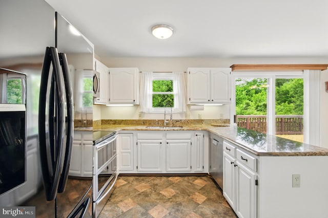 5762 Lichenbark Cir, New Market, MD 21774 - kitchen featuring appliances with stainless steel finishes, a sink, a peninsula, stone finish flooring, and white cabinetry