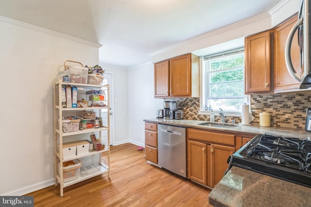45 W Woodland Ave, Springfield, PA 19064 - kitchen featuring appliances with stainless steel finishes, a sink, ornamental molding, decorative backsplash, and light wood-type flooring