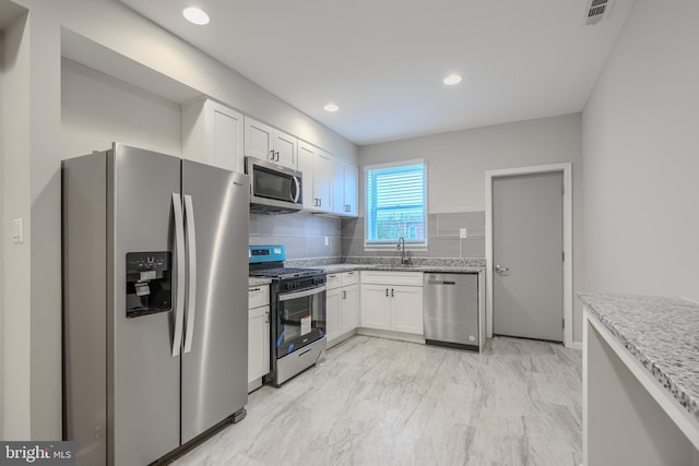 1229 N Potomac St, Baltimore, MD 21213 - kitchen featuring stainless steel appliances, a sink, white cabinetry, light marble finish flooring, and recessed lighting