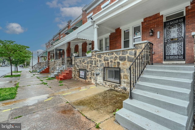 1229 N Potomac St, Baltimore, MD 21213 - view of exterior entry featuring a porch, brick siding, and stone siding