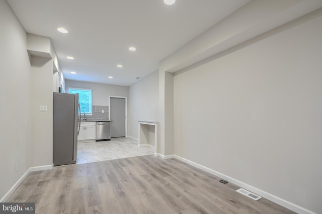 1229 N Potomac St, Baltimore, MD 21213 - unfurnished living room with light wood-style floors, baseboards, recessed lighting, and a sink