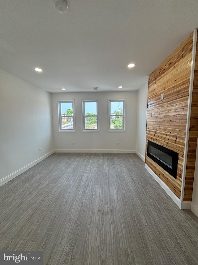 1748 N Chester St, Baltimore, MD 21213 - unfurnished living room with a large fireplace, wood finished floors, plenty of natural light, recessed lighting, and wood walls