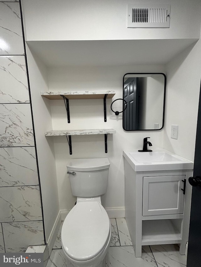 1748 N Chester St, Baltimore, MD 21213 - bathroom with marble look tile flooring, vanity, baseboards, and toilet