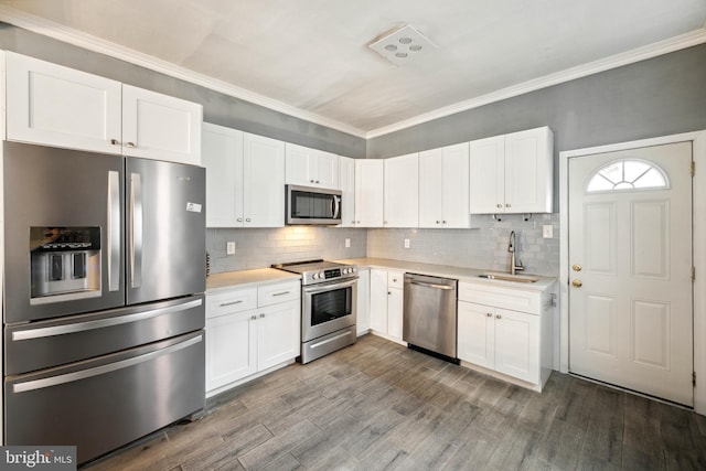 267 S 63rd St, Philadelphia, PA 19139 - kitchen featuring stainless steel appliances, a sink, light countertops, white cabinetry, and crown molding
