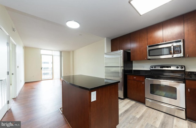155 Potomac Psge Unit 429, Oxon Hill, MD 20745 - kitchen featuring appliances with stainless steel finishes, light wood-style flooring, dark countertops, a kitchen island, and open floor plan