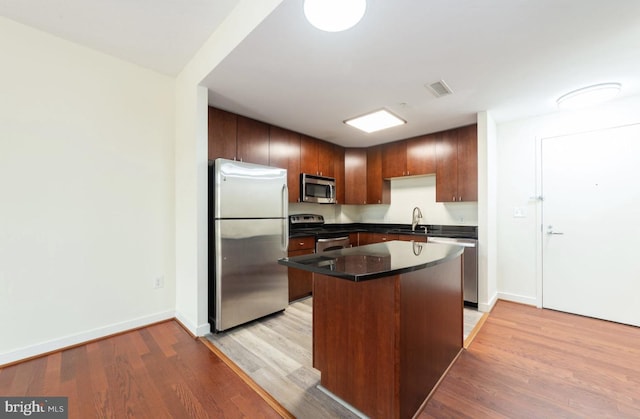 155 Potomac Psge Unit 429, Oxon Hill, MD 20745 - kitchen featuring appliances with stainless steel finishes, a sink, light wood-type flooring, dark countertops, and a center island