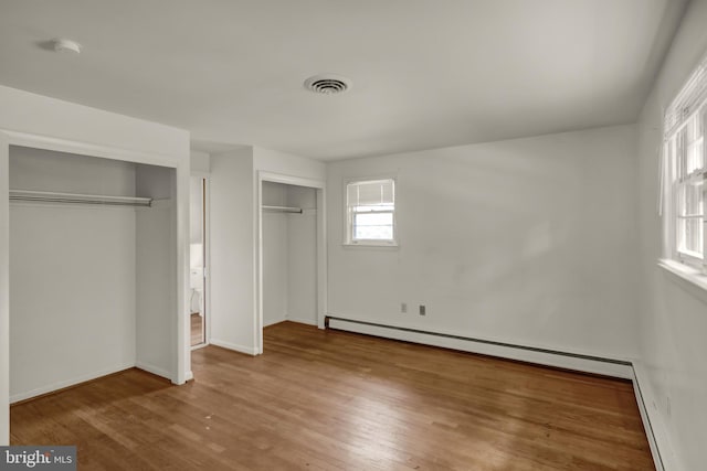 1401 Rockland St, Reading, PA 19604 - unfurnished bedroom featuring wood finished floors, baseboards, a baseboard radiator, and two closets