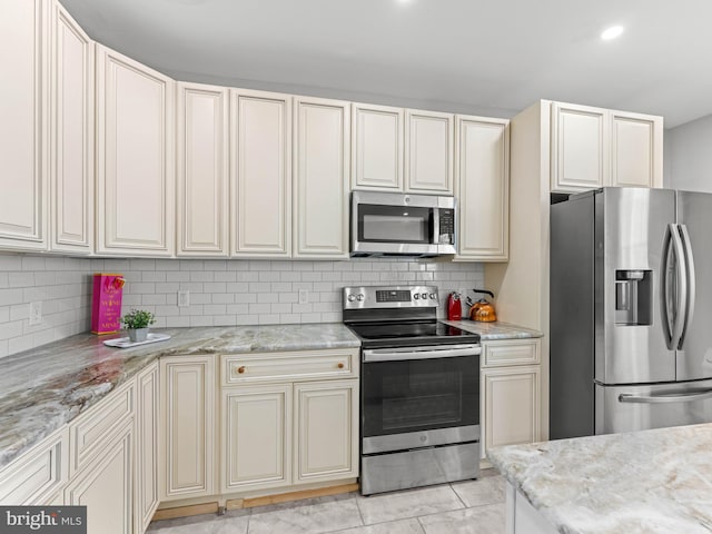 285 N Lansdowne Ave, Lansdowne, PA 19050 - kitchen with appliances with stainless steel finishes, backsplash, light stone counters, and cream cabinetry